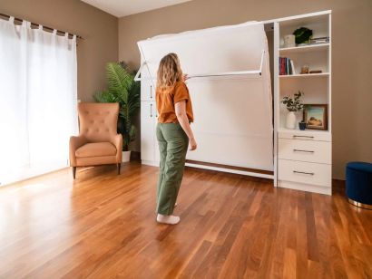 Girl opening a white Murphy bed in a modern room setting
